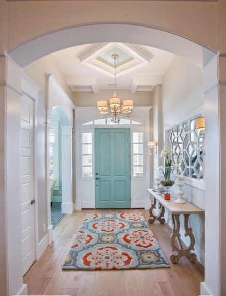 Coastal foyer with turquoise door and chandelier
